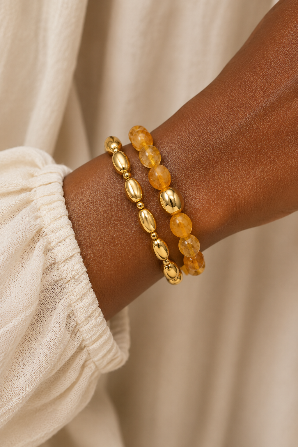 Amber and gold-tone stretch bracelet set worn stacked on a woman's wrist