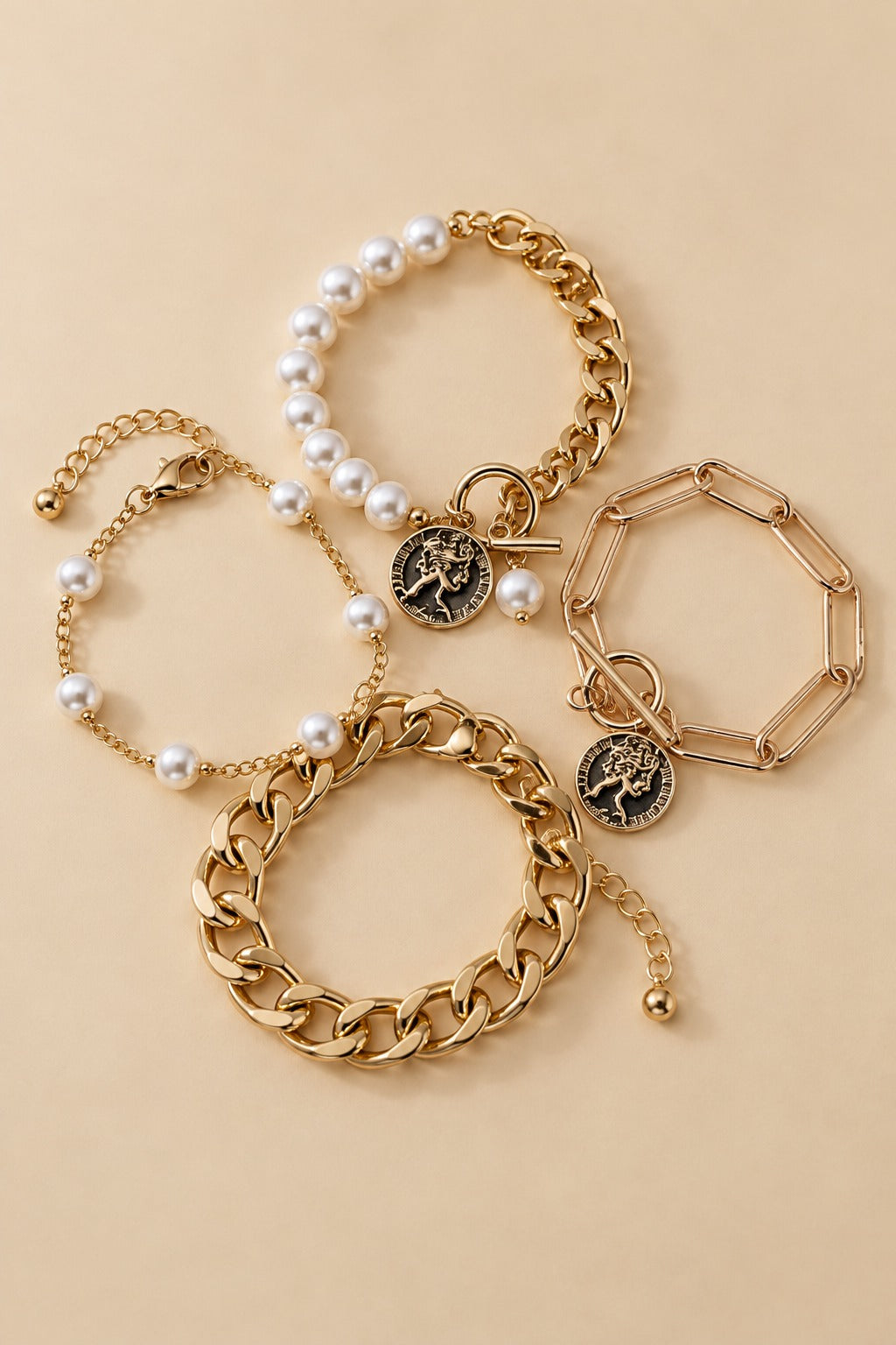 Gold-tone pearl bracelet set arranged in a natural layered flat lay on a warm beige background.