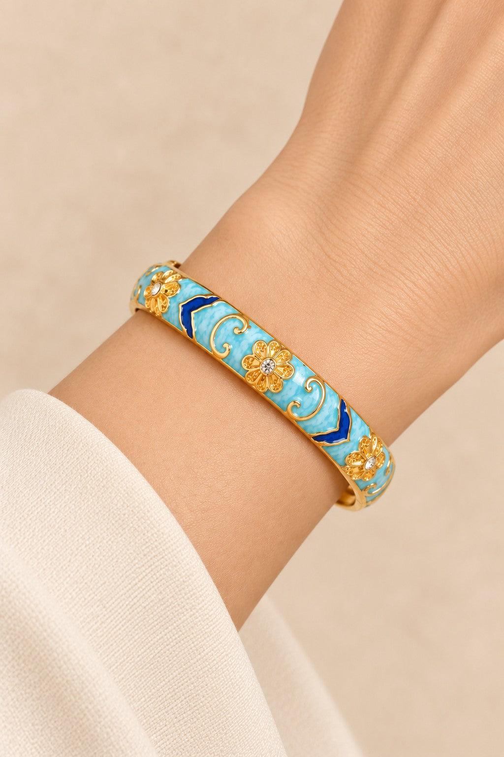 Close-up detail of light blue and dark blue enamel gold-tone hinged bangle
