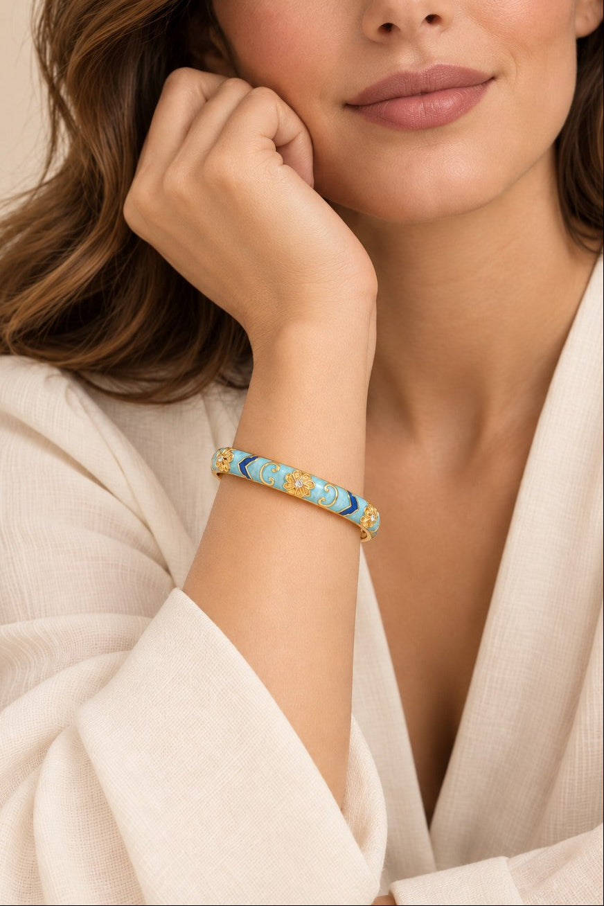 Light blue and dark blue enamel gold-tone hinged bangle worn on wrist