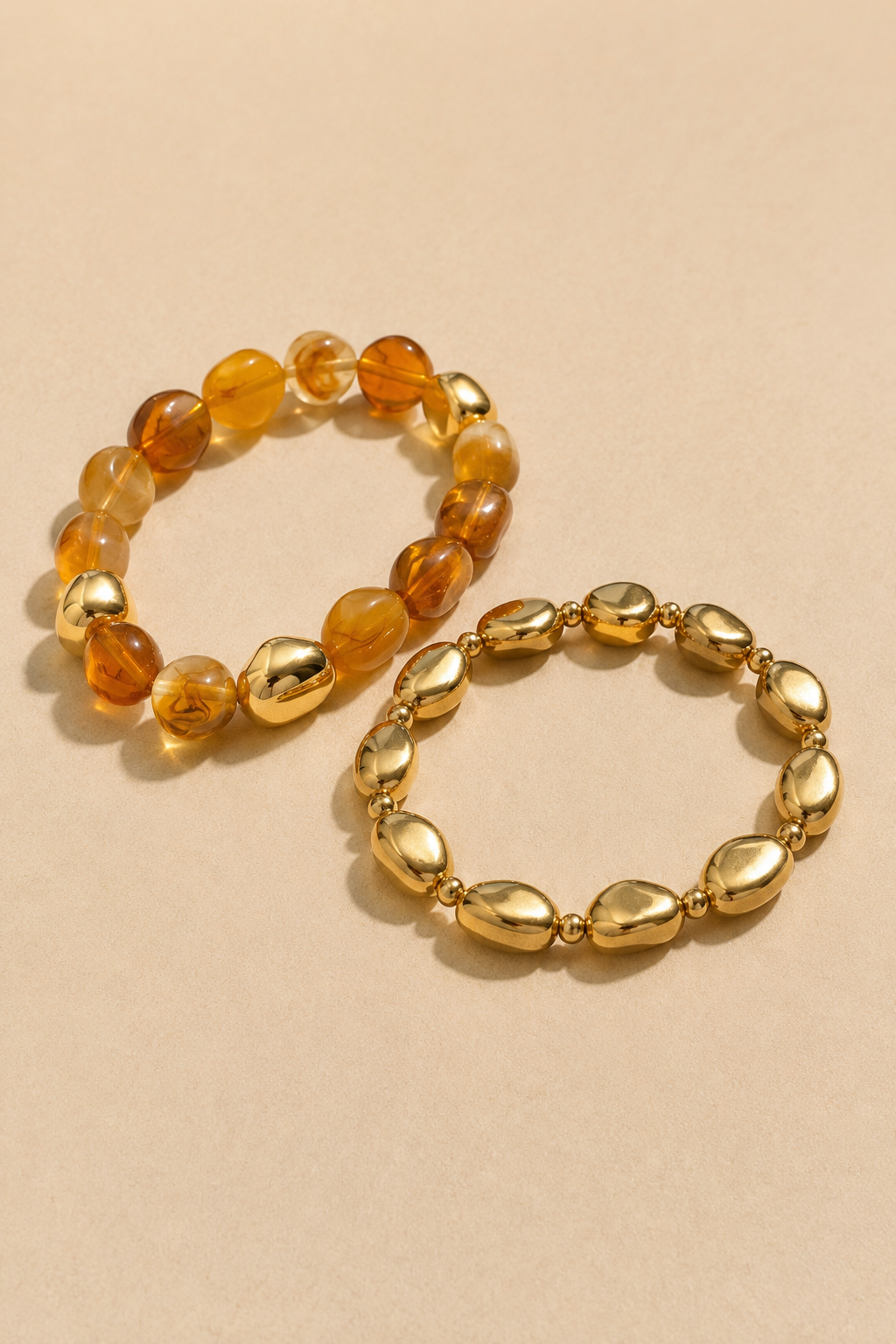 Amber and gold-tone stretch bracelets shown separately on warm beige background