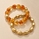 Amber and gold-tone stretch bracelet set layered on warm beige background