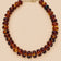 Brown translucent beaded necklace with gold-tone clasp on beige background