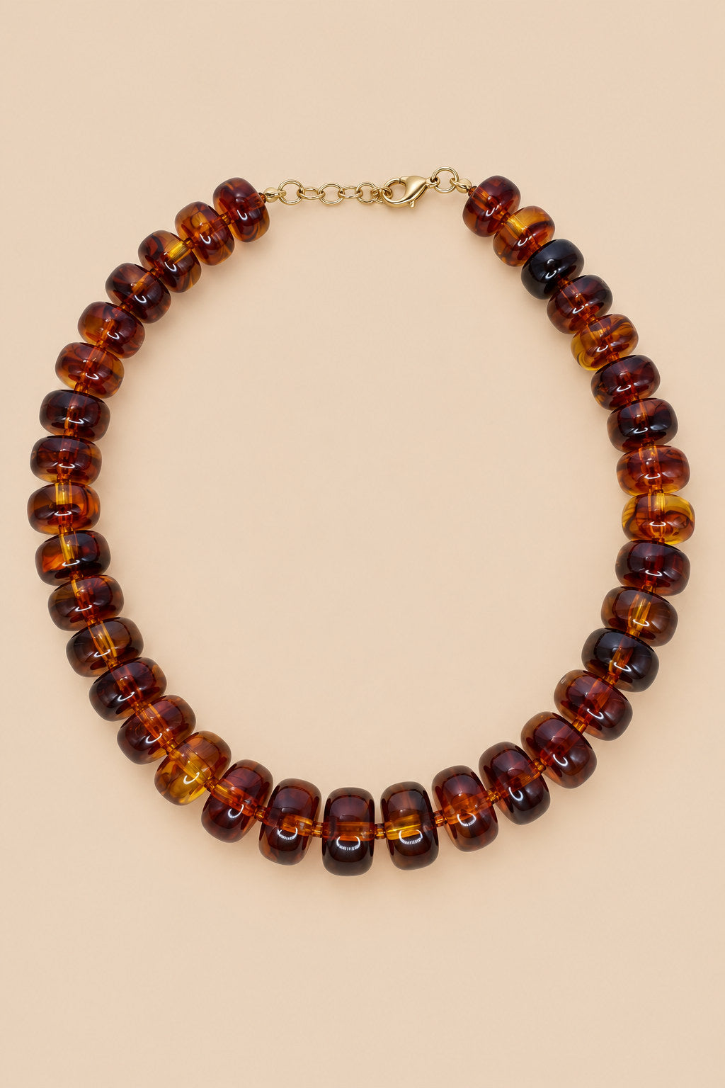 Brown translucent beaded necklace with gold-tone clasp on beige background