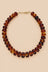 Brown translucent beaded necklace with gold-tone clasp on beige background
