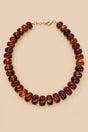 Brown translucent beaded necklace with gold-tone clasp on beige background