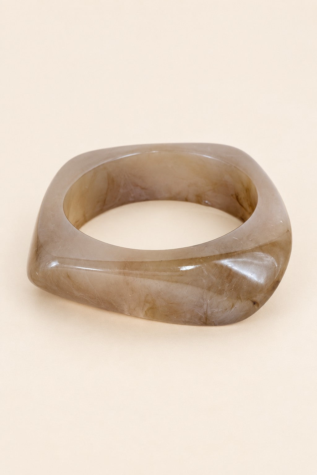 Coffee-tone geometric resin bangle on a plain beige background.