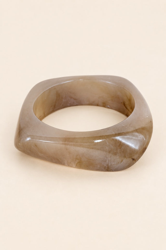 Coffee-tone geometric resin bangle on a plain beige background.