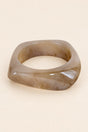 Coffee-tone geometric resin bangle on a plain beige background.