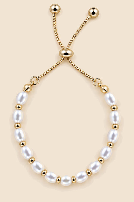 Close-up view of a gold-tone pearl slider bracelet.