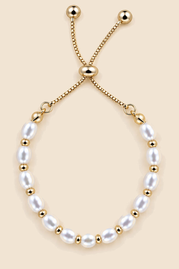 Close-up view of a gold-tone pearl slider bracelet.