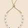 Gold-tone pearl slider bracelet on a beige background.