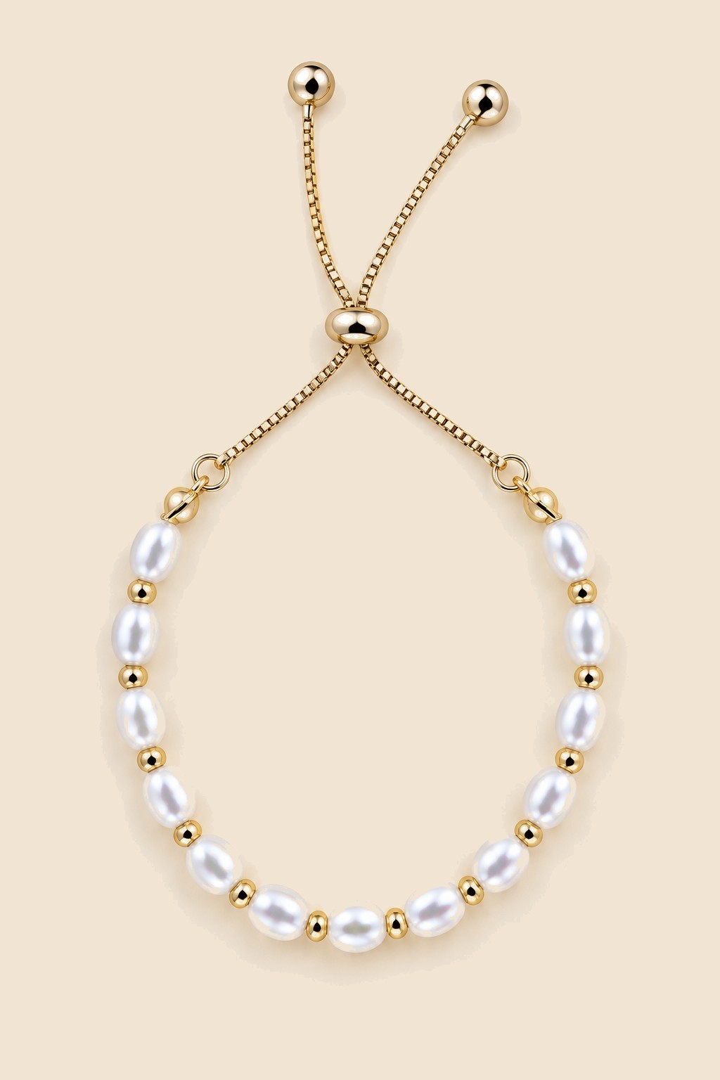 Gold-tone pearl slider bracelet on a beige background.