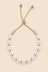 Gold-tone pearl slider bracelet on a beige background.