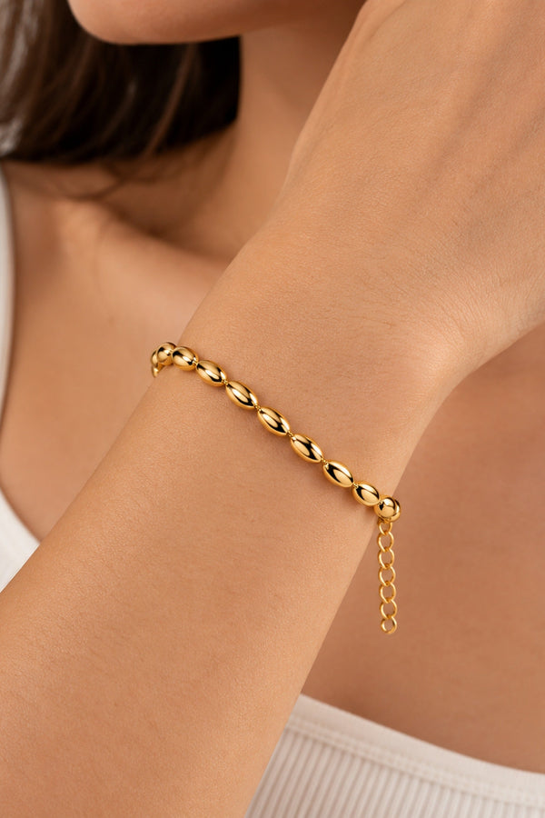 Gold-tone oval-bead bracelet worn on the wrist.