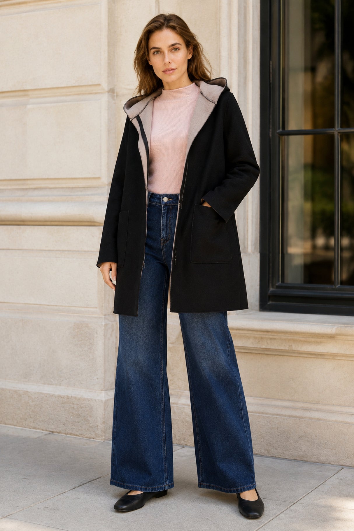 Manteau noir à capuchon Holly porté dehors avec jean foncé à jambe large
