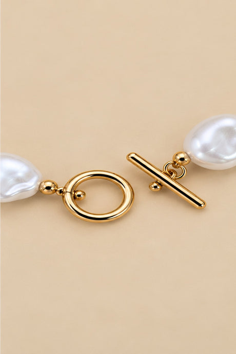 Close-up of the irregular pearl bracelet toggle clasp and gold-tone details.