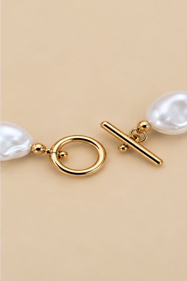 Close-up of the irregular pearl bracelet toggle clasp and gold-tone details.
