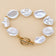 Irregular pearl bracelet with gold-tone spacers and toggle clasp on beige background.
