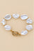 Irregular pearl bracelet with gold-tone spacers and toggle clasp on beige background.