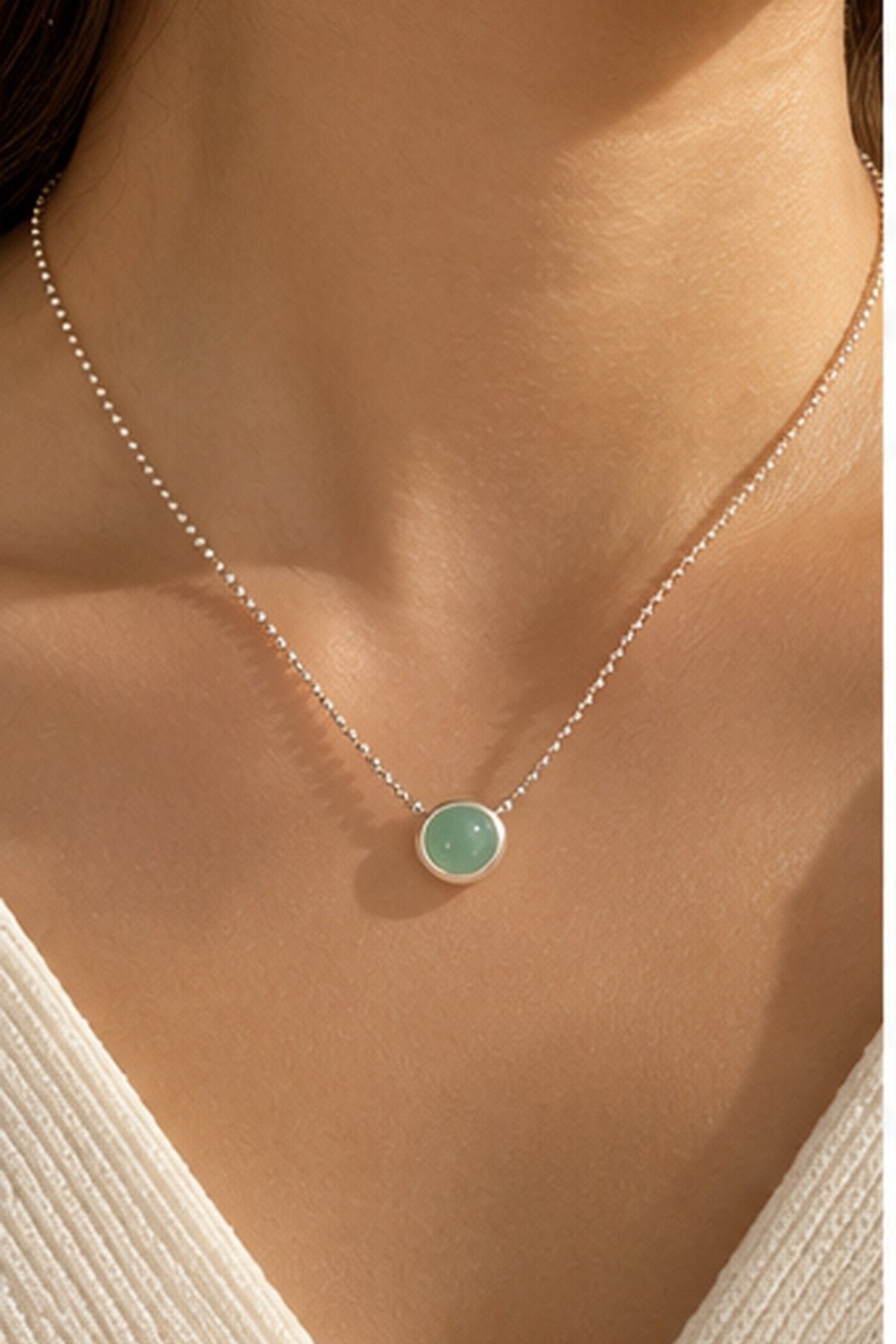 Collier argenté à pendentif vert menthe porté au cou