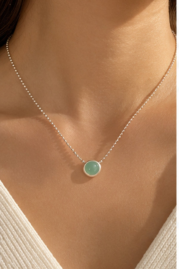 Collier argenté à pendentif vert menthe porté au cou
