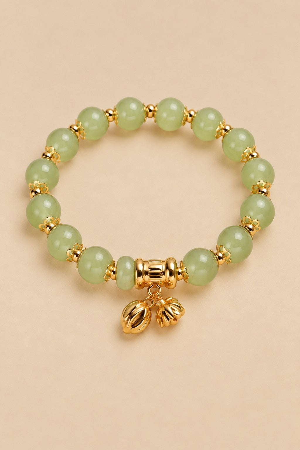 Pale green beaded charm bracelet with gold-tone charms on an ONZE beige background.
