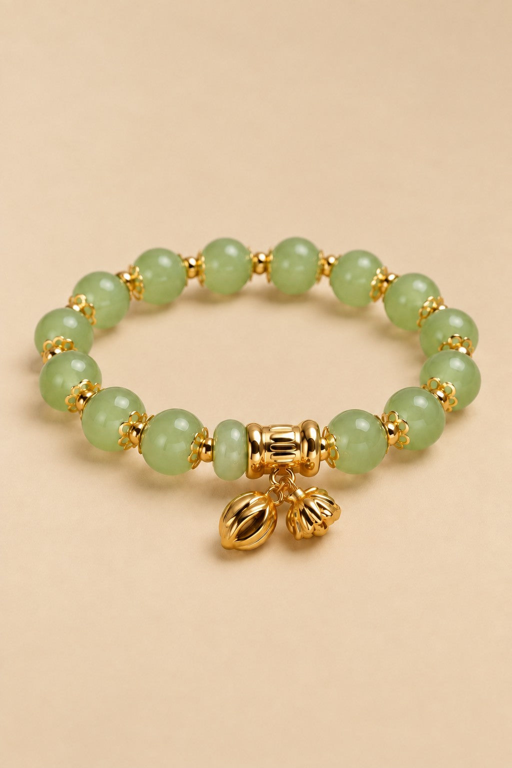 Pale green beaded charm bracelet with gold-tone details on an ONZE beige background.