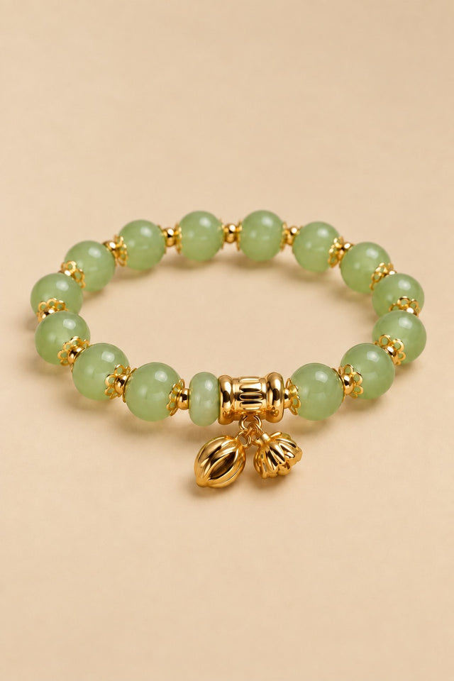 Pale green beaded charm bracelet with gold-tone details on an ONZE beige background.
