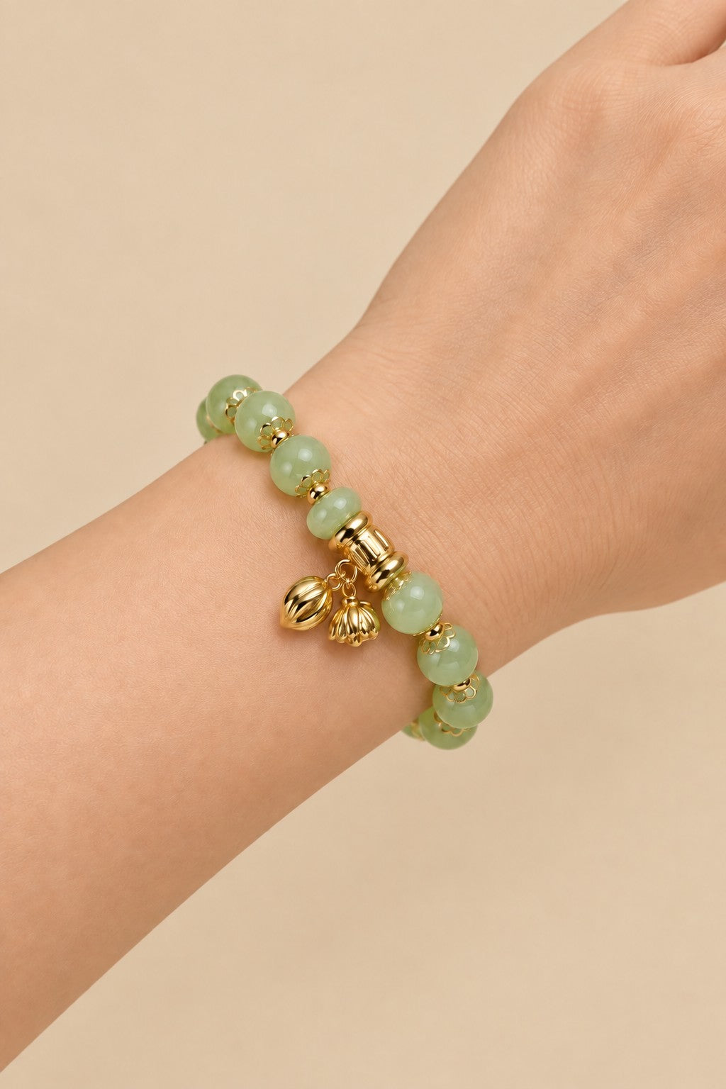 Pale green beaded charm bracelet worn on the wrist.