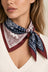 Model wearing a patchwork paisley square scarf in navy, ivory and burgundy