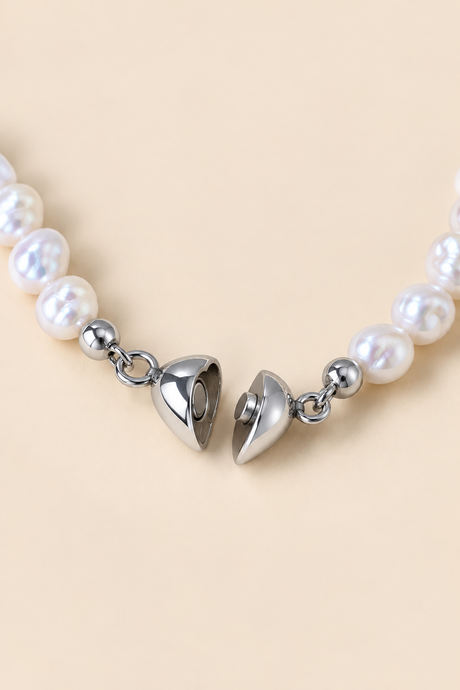 Close-up of the silver-tone heart clasp on the irregular white pearl bracelet shown open.