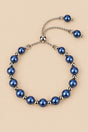 Blue pearl slider bracelet on ONZE beige background.