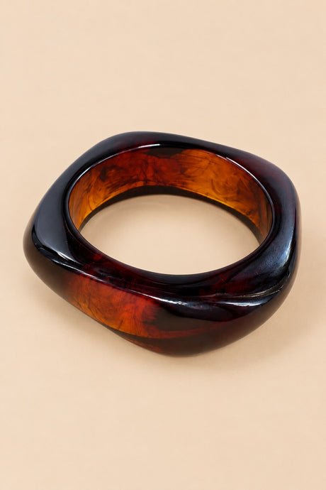 Close-up of the red amber geometric bangle showing its glossy rounded-square silhouette.