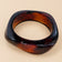 Red amber geometric bangle on a warm beige background.
