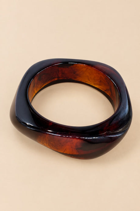 Red amber geometric bangle on a warm beige background.