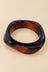 Red amber geometric bangle on a warm beige background.