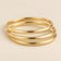Three-ring gold-tone bangle set on beige background