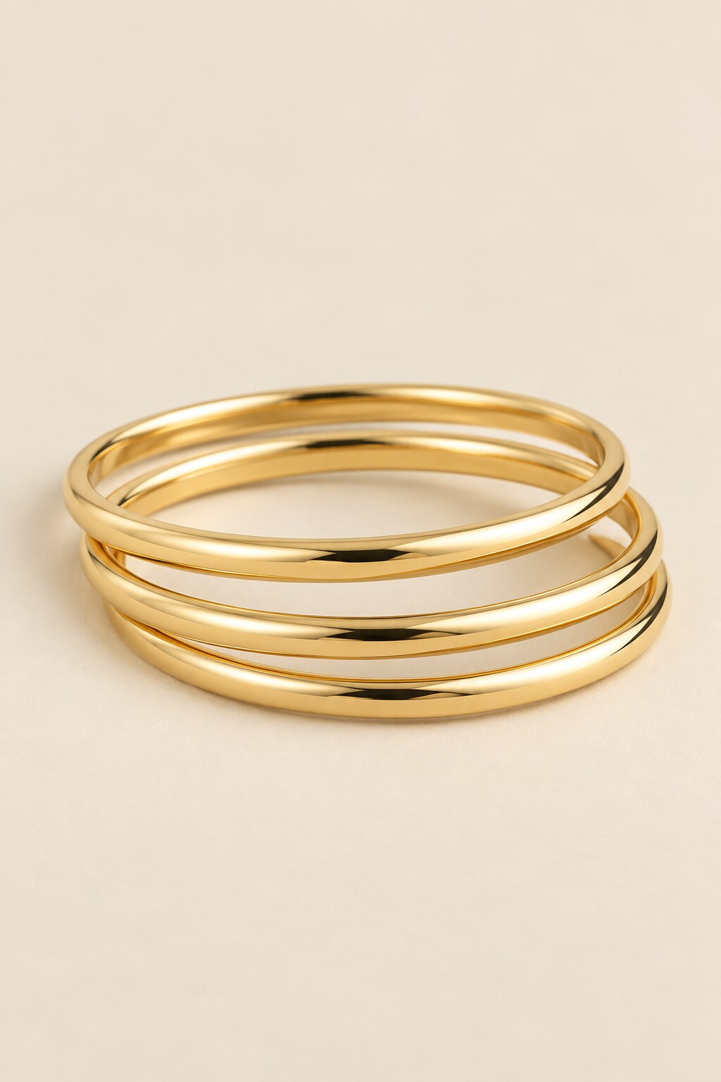 Three-ring gold-tone bangle set on beige background
