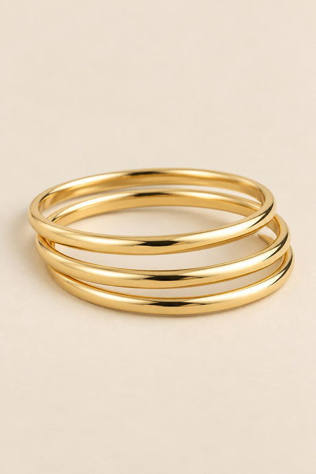Three-ring gold-tone bangle set on beige background