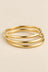 Three-ring gold-tone bangle set on beige background