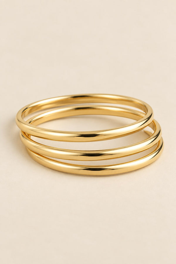 Three-ring gold-tone bangle set on beige background